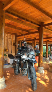 Nguyễn Anh Tuấn trên chiếc BMW F800GS dưới mái nhà sàn gỗ vùng cao